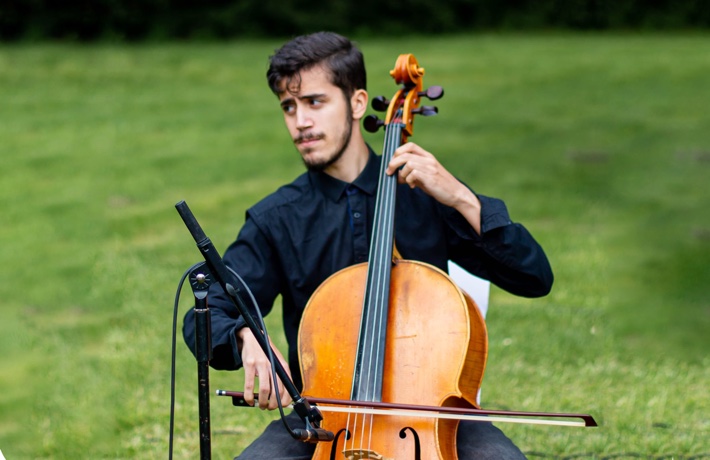 Yanis Boudris jouant du violoncelle en plein air.