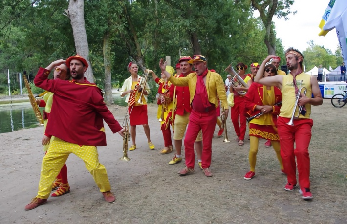 La fanfare défilant et jouant en extérieur, habillée tout en jaune et rouge.