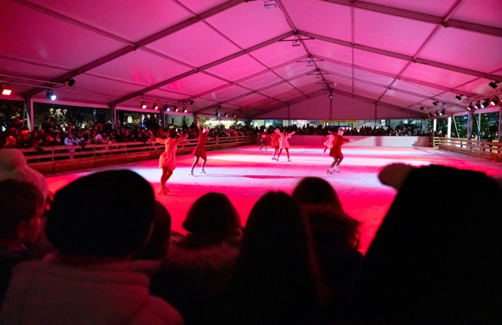 Des danseuses en patins font une chorégraphie sur la glace.