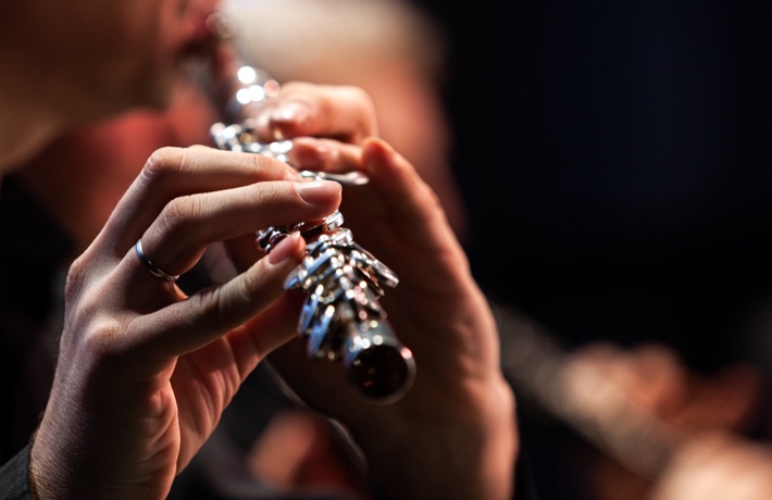 Gros plan sur les doigts d’une flutiste en train de jouer la flûte traversière.