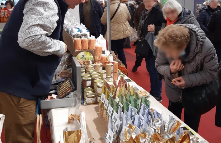 Des personnes s’approchent des produits exposés par un producteur sur une table.