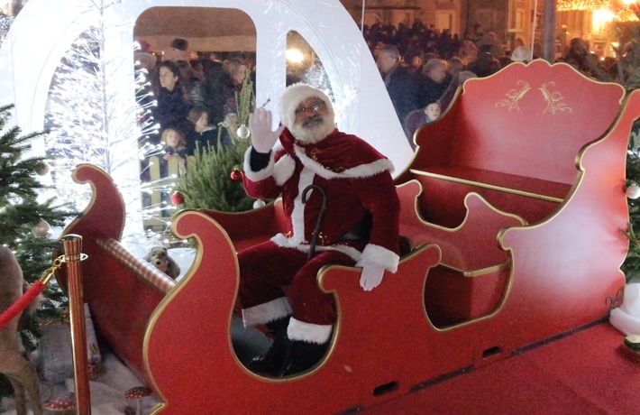 Le père Noël fait coucou de la main depuis son traîneau.