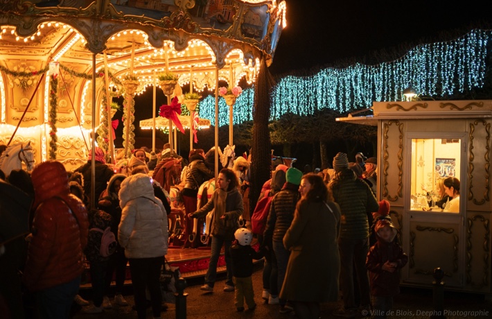 Les parents et leurs enfants s’affairent autour du carrousel qui brille et les illumine.